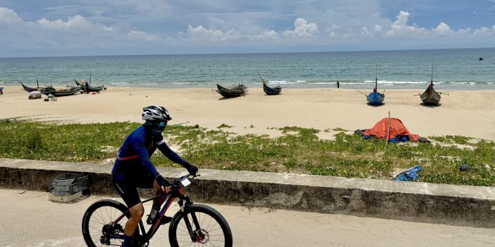 Cyclist pedaling by beach