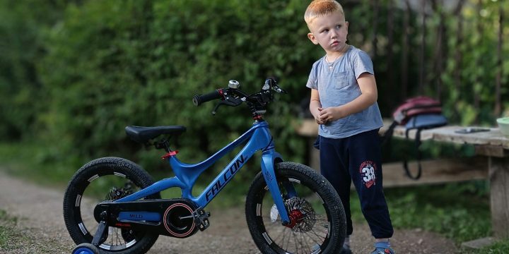 Little boy next to bike on training wheels